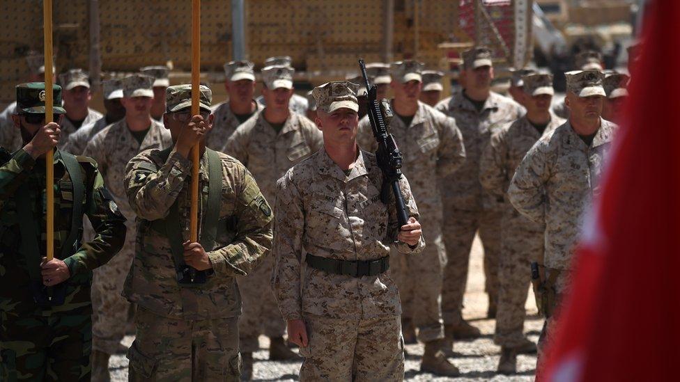 US Marines and Afghan National Army (ANA) soldiers carry flags during a handover ceremony at Leatherneck Camp in Lashkar Gah in the Afghan province of Helmand on 29 April 2017