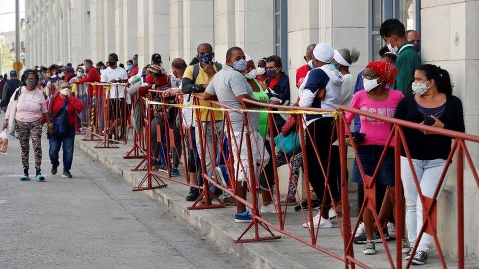 People wearing masks line up to buy food in a market in Havana, Cuba, 02 February 2021.