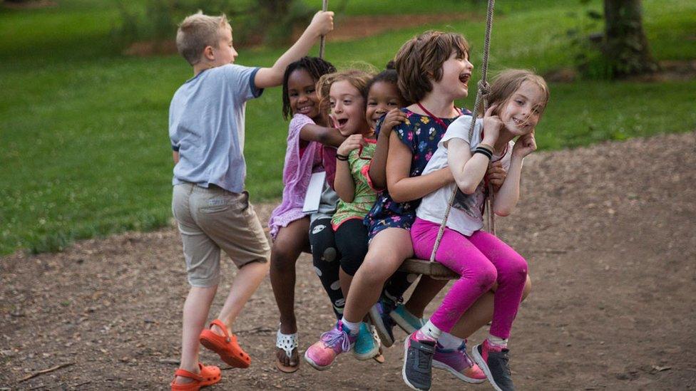 A-group-of-children-playing-on-a-big-rope-swing-in-a-park.