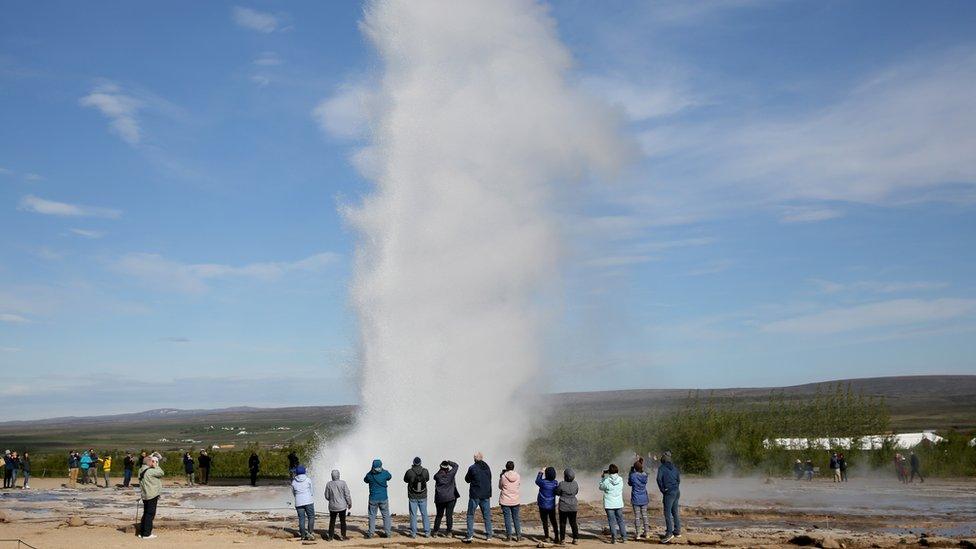 Tourists stand around a Geyser in Iceland