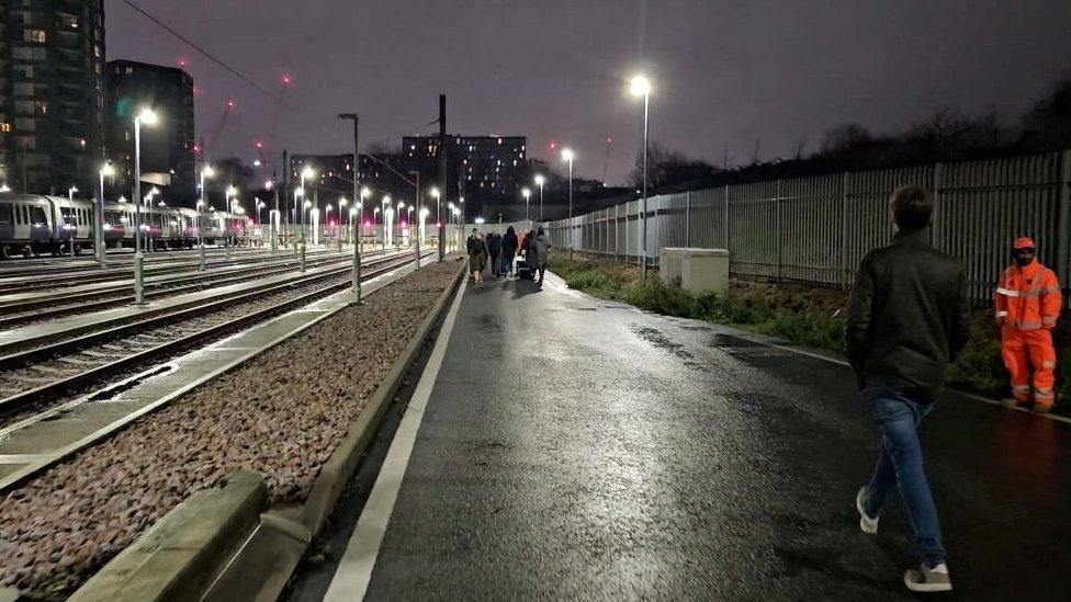 Passengers walk after being evacuated from trains stuck on the Elizabeth line