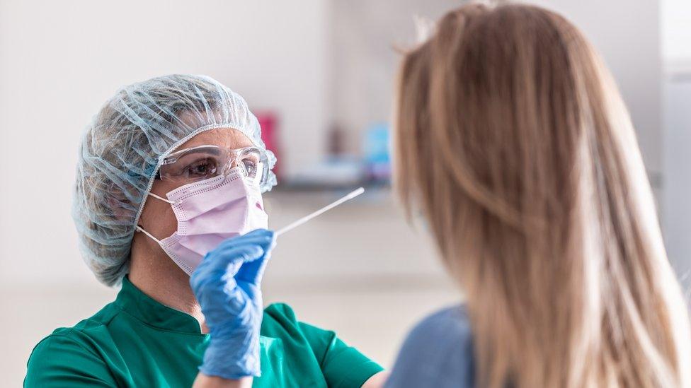 Medical staff in protective gear administers swab test