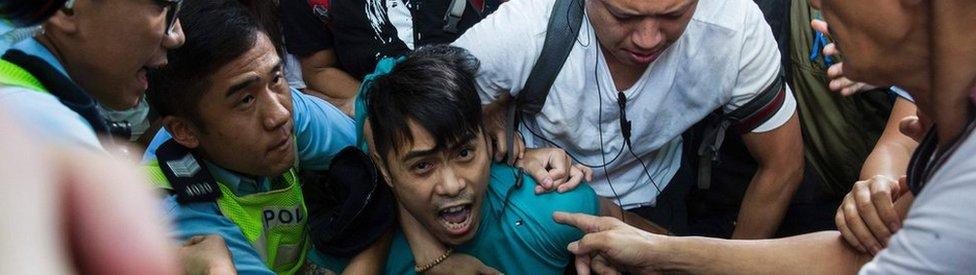 A pro-Beijing supporter is forcibly removed by police as he tries to stop a League of Social Democrats protest in Hong Kong, 1 July 2017