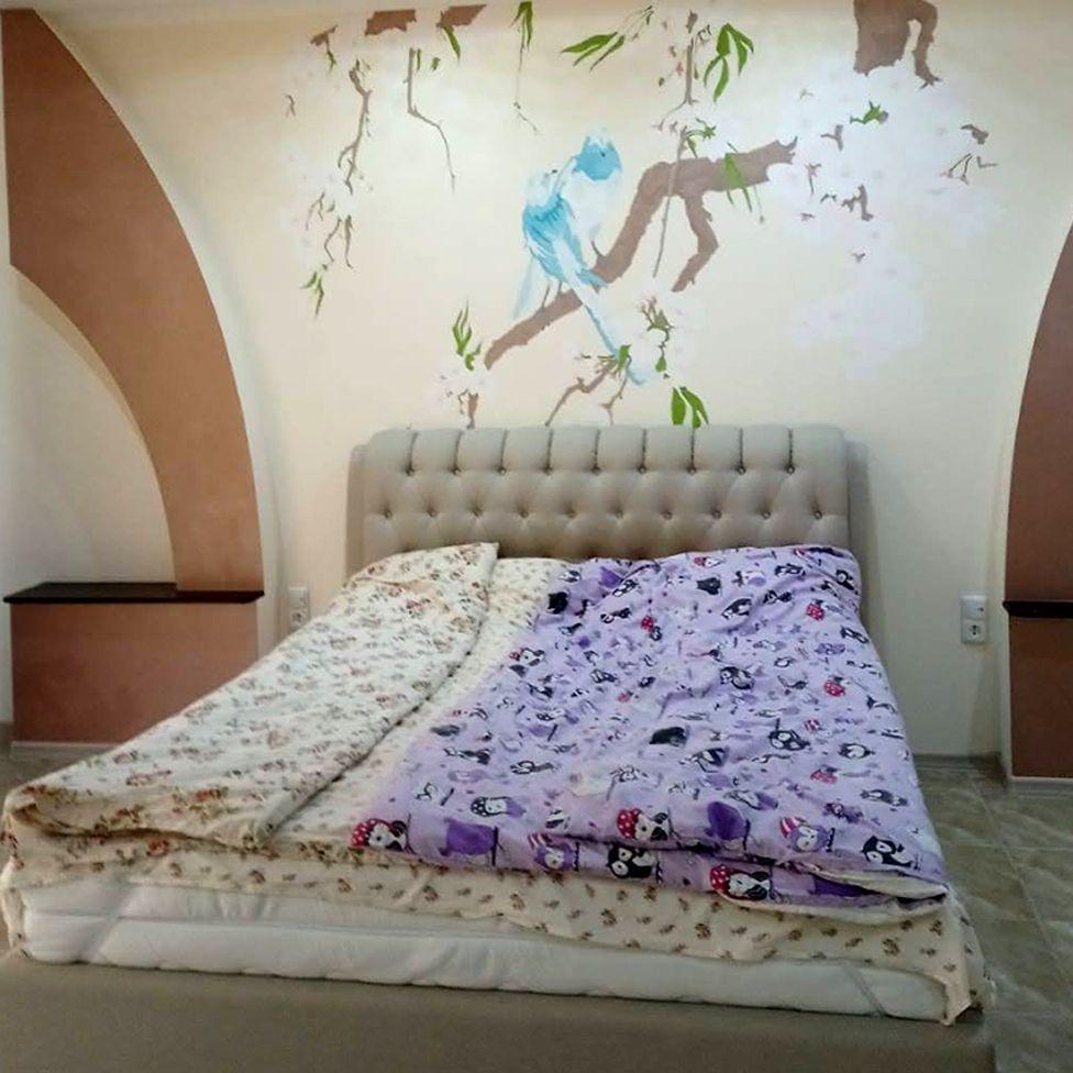 Bedroom with cherry blossom and doves painted on the wall by the bed.