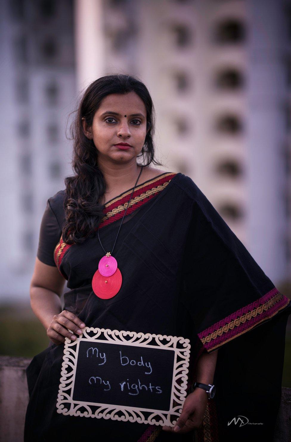 Remya Saseendran holds a poster that says "My body, my rights"