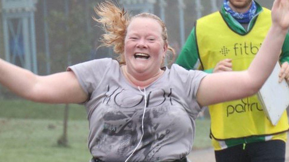 Dawn Nisbet crossing the finish line with her hands in the air and a big smile on her face