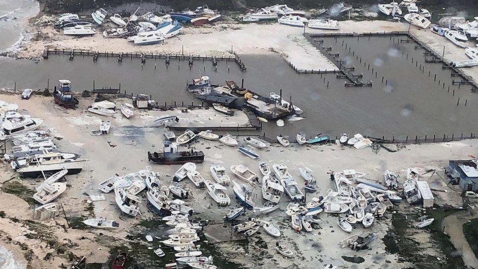 An aerial photo of a harbour with many boats pushed out of the sea and destroyed