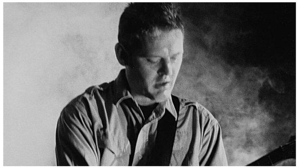 A black and white photo of Bruschini with his guitar