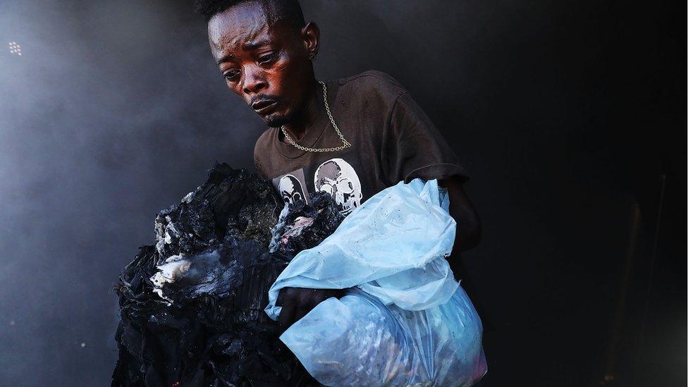 A trader carries his fire-damaged inventory.