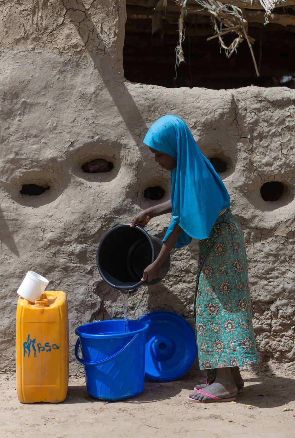 Malika pours water into a bucket in Norandé