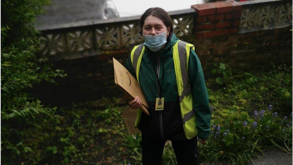 Cath is wearing a facemask as she delivers a parcel to someone's house