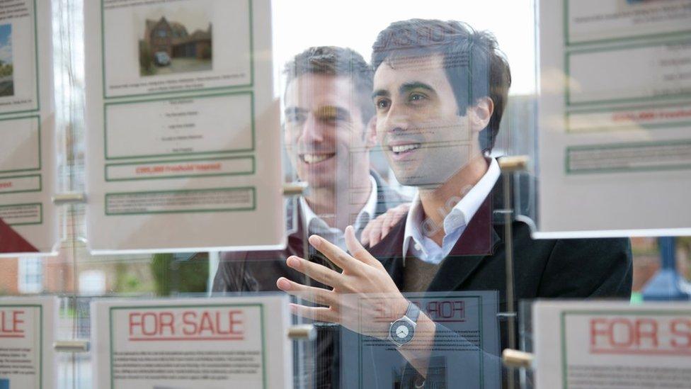 Couple looking at estate agent windows (generic)