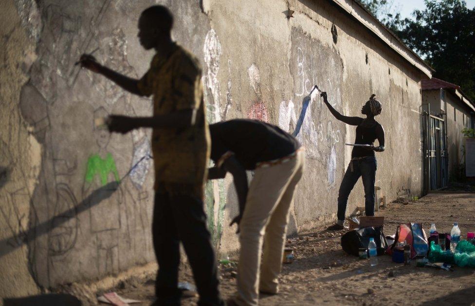 Artists paint on concrete wall