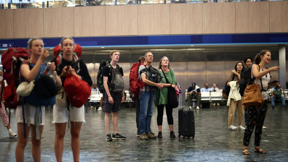 People look at departure information screens at Euston railway station