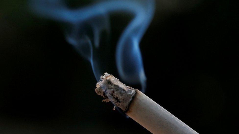 A lit cigarette against a black background