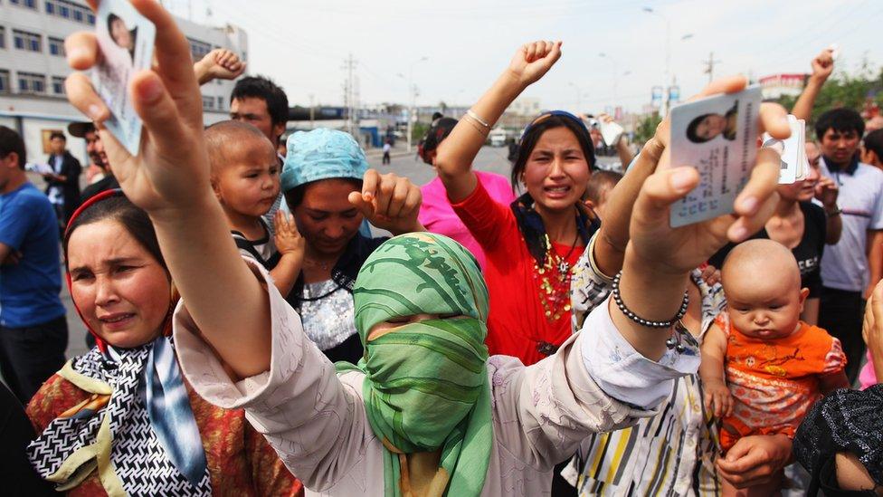 A Uighur woman holds ID cards at a protest in Xinjiang Uighur autonomous region, China