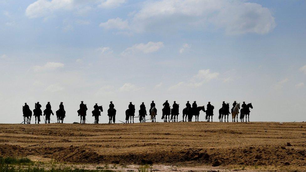 Police on horses guard the grounds of the coal mine