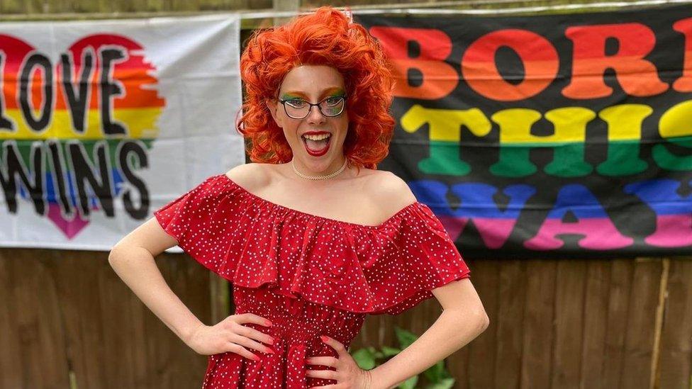 Korben posing in a red polka dot dress and red wig as Miss Frou Frou at Brickies Pride in Norwich in July 2021