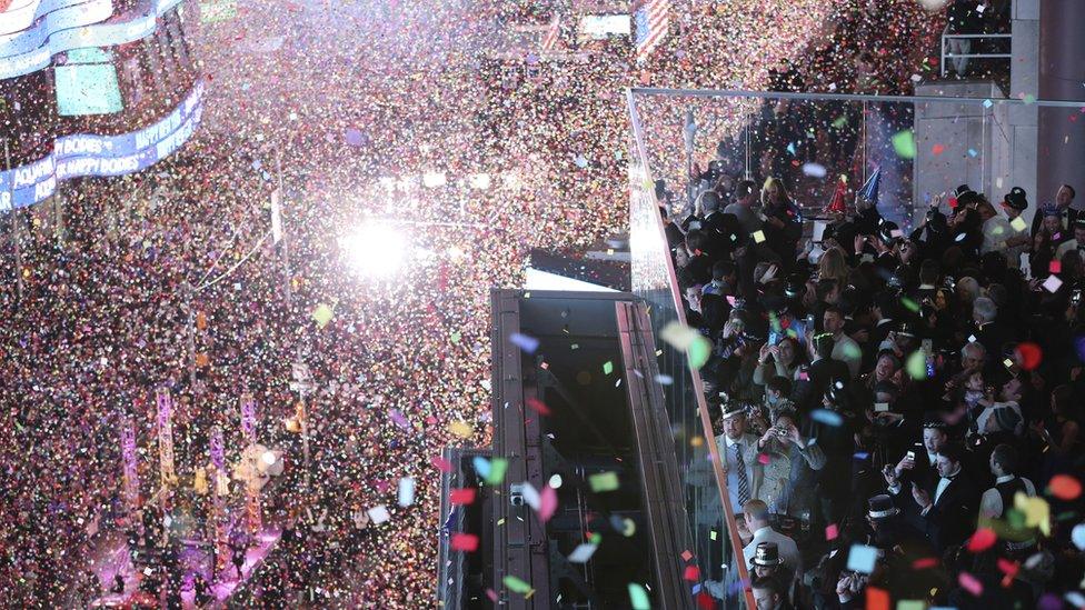 Revellers celebrate as confetti flies over New York"s Times Square after the clock strikes midnight