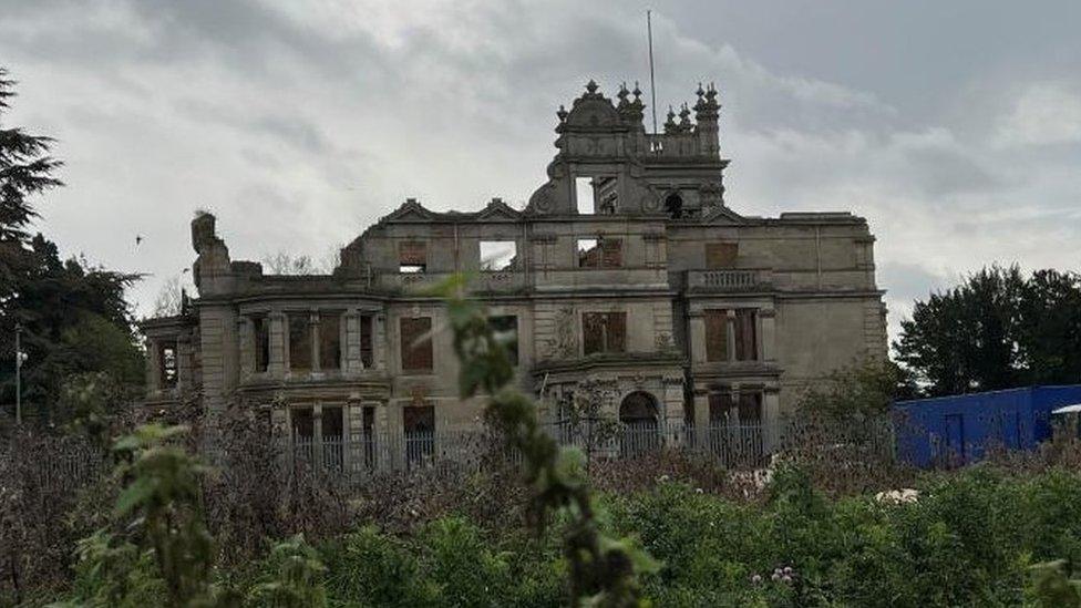 Ruin of three-story stately home with towers. Roof is missing.