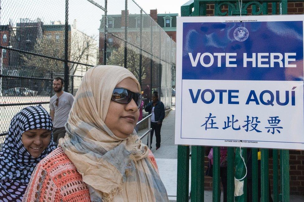 Two women with Muslim headscarves walk past a voting sign in the Brooklyn borough of New York City.