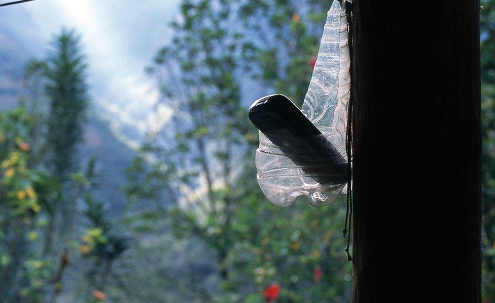 A mobile phone suspended in a cut water bottle.