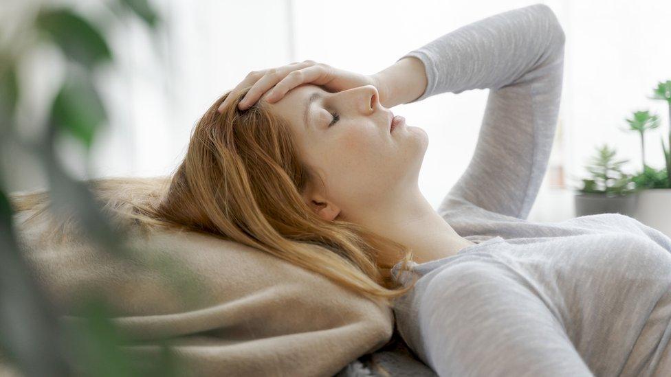 young woman lying down with hand on her head