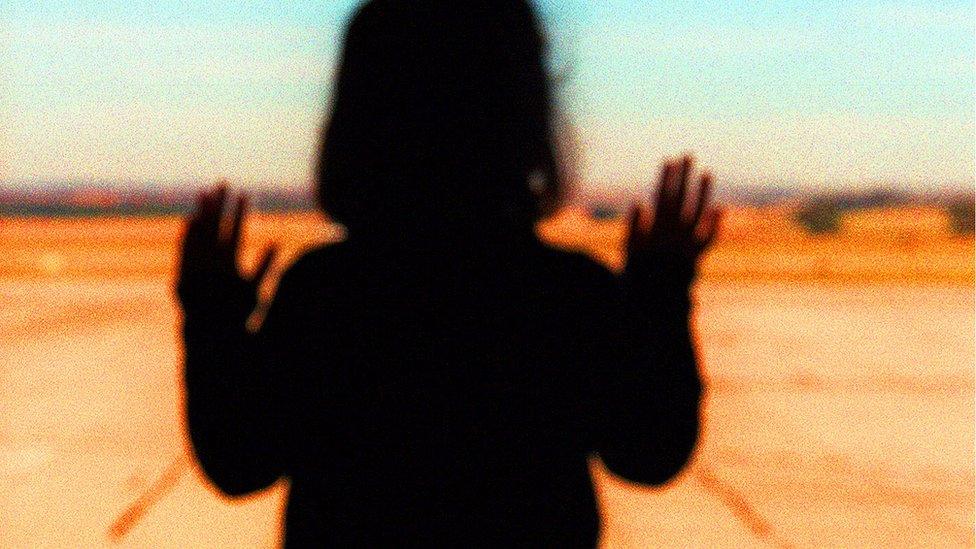 Silhouette of a young girl against a barren landscape