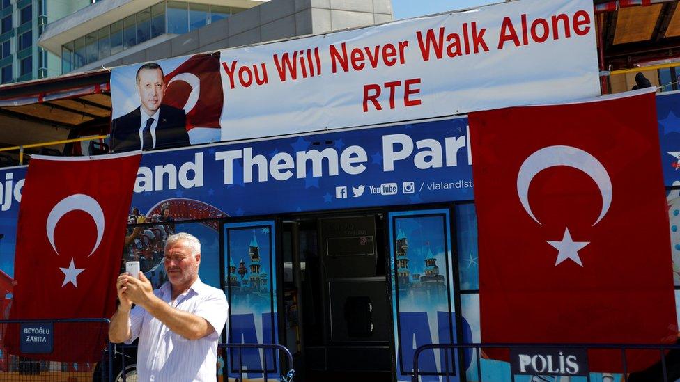 A man takes a selfie with a tourist bus at Taksim square in central Istanbul