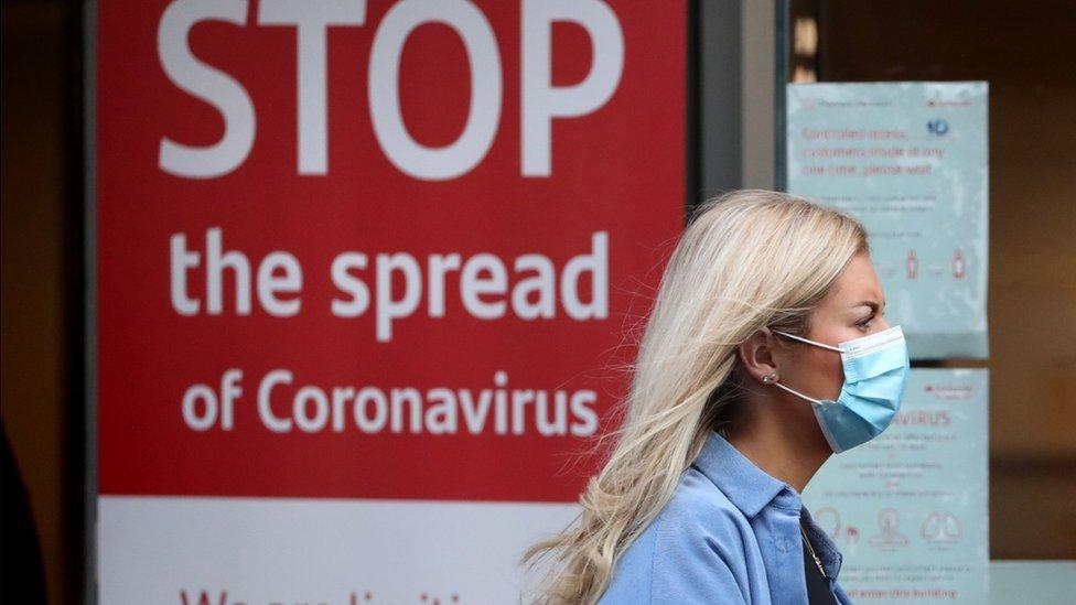 Woman walking past a Covid warning sign