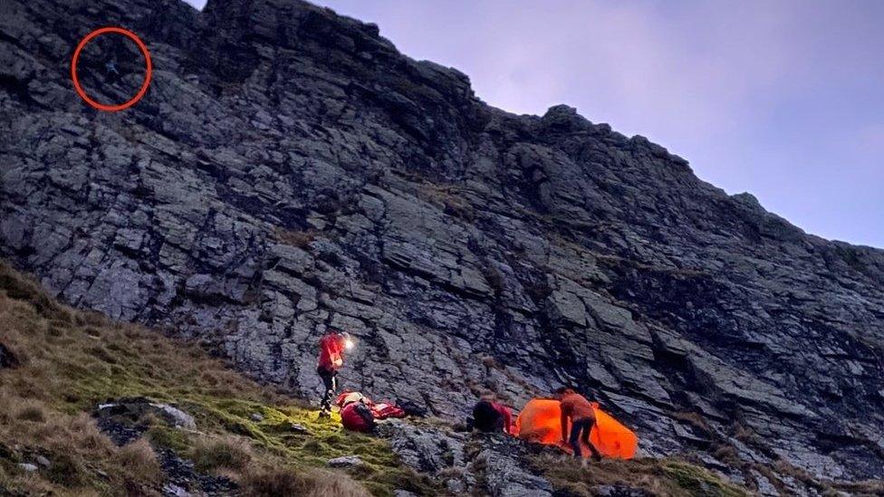 Picture shows the rescue team on the ground with the man, with a red circle marking where the woman was stuck