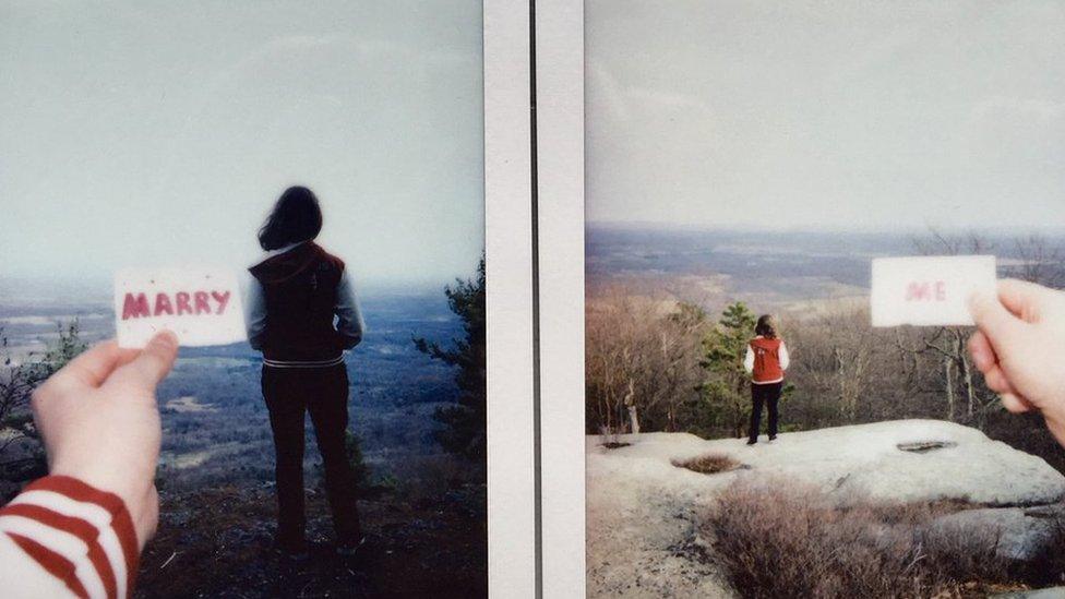 Two photos with Meg's back to the camera - one with a card held up behind her saying 'Marry', the other with a card saying 'Me'