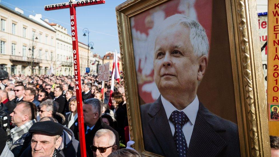 People hold a portrait of late Polish President Lech Kaczynski as they attend a ceremony marking the fifth anniversary of the presidential plane crash in Smolensk