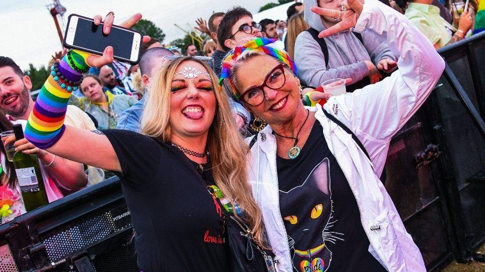 Two women in rainbow garb dance to music