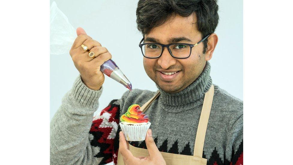 Rahul ices a rainbow cupcake