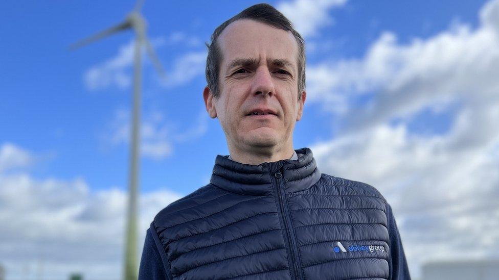 Andy Brand from The Abbey Group, standing by a wind turbine in Chatteris