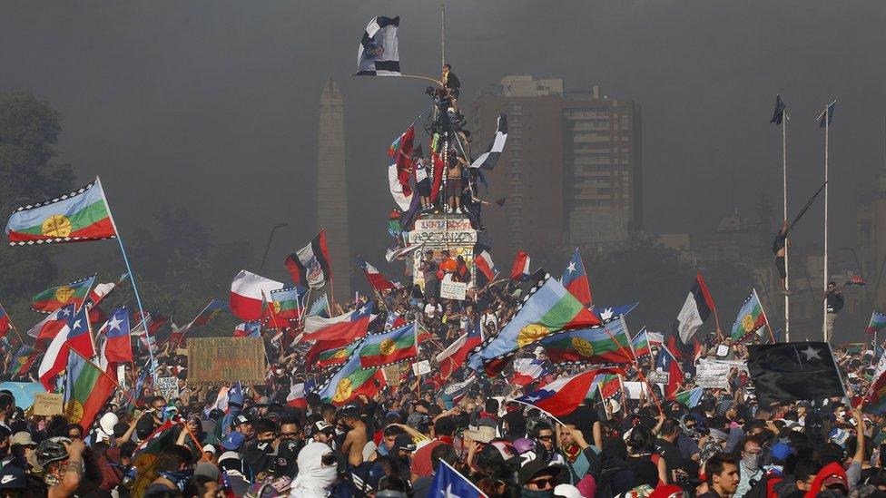 Protesters shout slogans and wave flags of Chile and the Mapuche people during a national strike and general demonstration called by different workers' unions on 12 November, 2019 in Santiago, Chile.