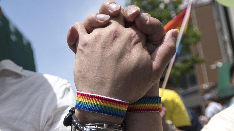 Two men hold hands, 6 May 2018