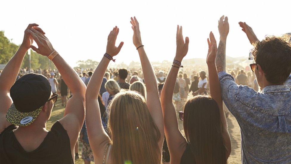 Festival-goers outside with their arms in the air