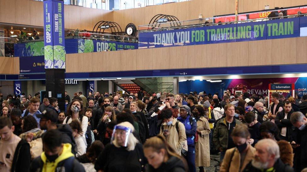 Passengers waiting at Euston under a COP26 sign thanking them for travelling by train