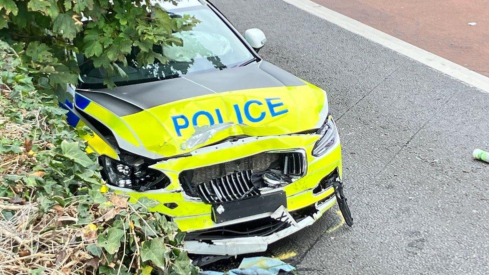 The smashed police car with its bonnet seriously damaged