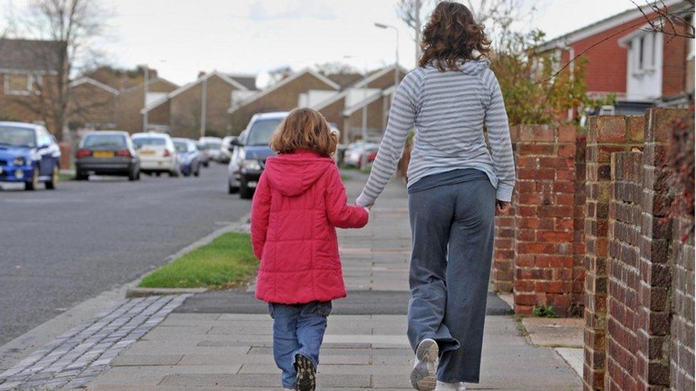 Mother and daughter walking along a street