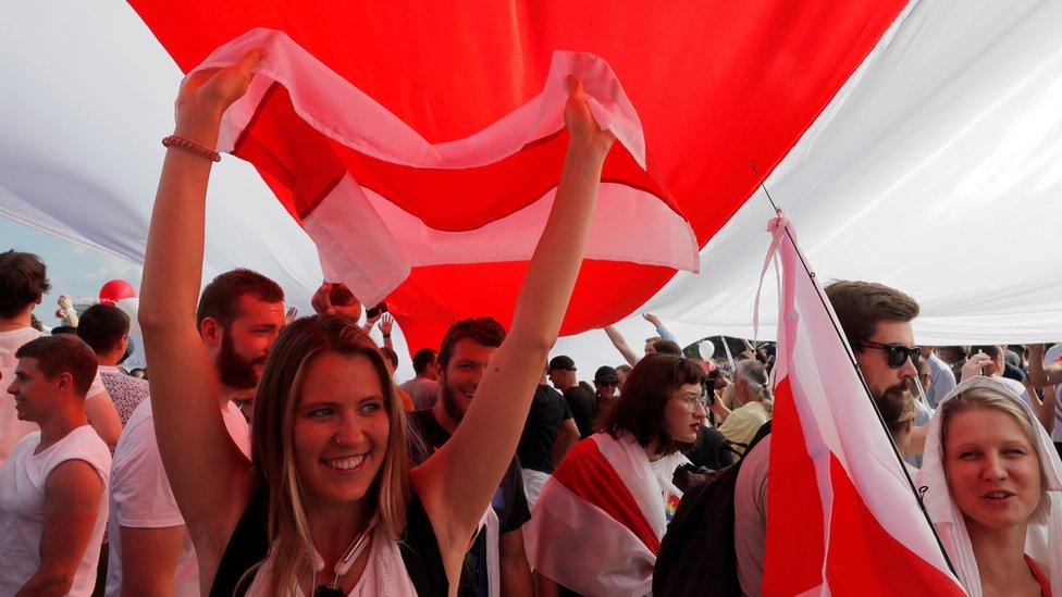 Demonstrators hold a giant historical white-red-white flag of Belarus during a protest against the presidential election results demanding the resignation of Belarusian President Alexander Lukashenko and the release of political prisoners, in Minsk, 16 August