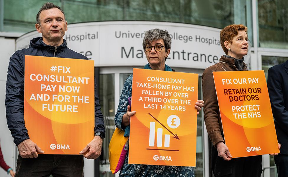 Three consultants hold orange placards outside UCLH on 19 September 2023