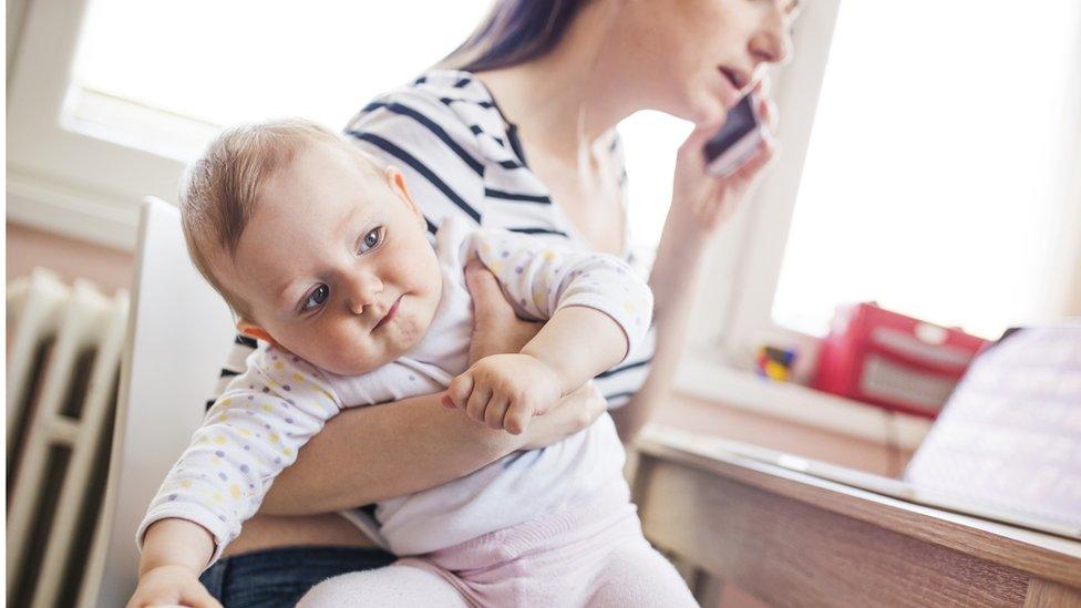 Mum holding a baby while on the phone