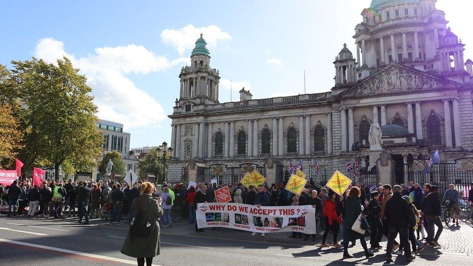 A crowd of people hols a protest against the cost-of-living crisis outside Belfast City Hall