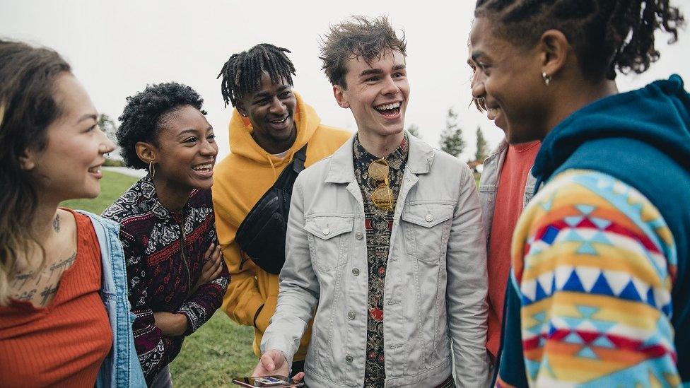 Small group of young friends are hanging out in a public park.