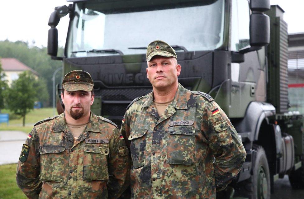 Corporal Christopher Seidel (L) and Staff sergeant Friedemann Frischko (R) stand in front of their army truck