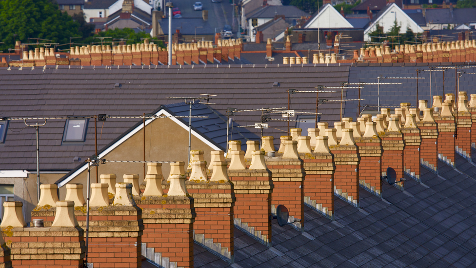 A picture of a row of house rooftops with chimneys