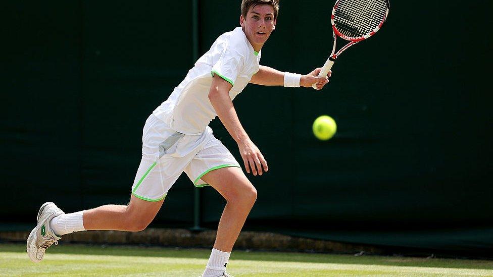 cameron lifts his racket up to prepare to hit a tennis ball